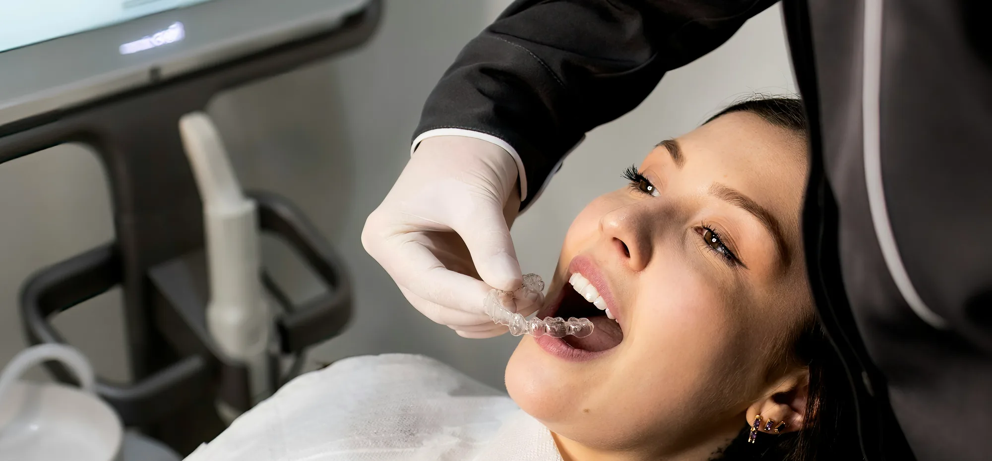Clinician fitting a clear aligner for a patient, with the digital scan on the screen beside them